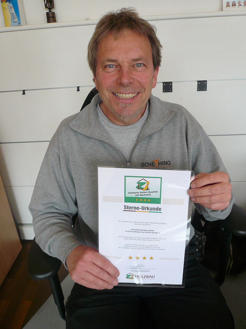 Ralf Scheyhing präsentiert stolz die Urkunde für die 4-Sterne-Zertifizierung durch den Baden-Württembergischen Holzbauverband